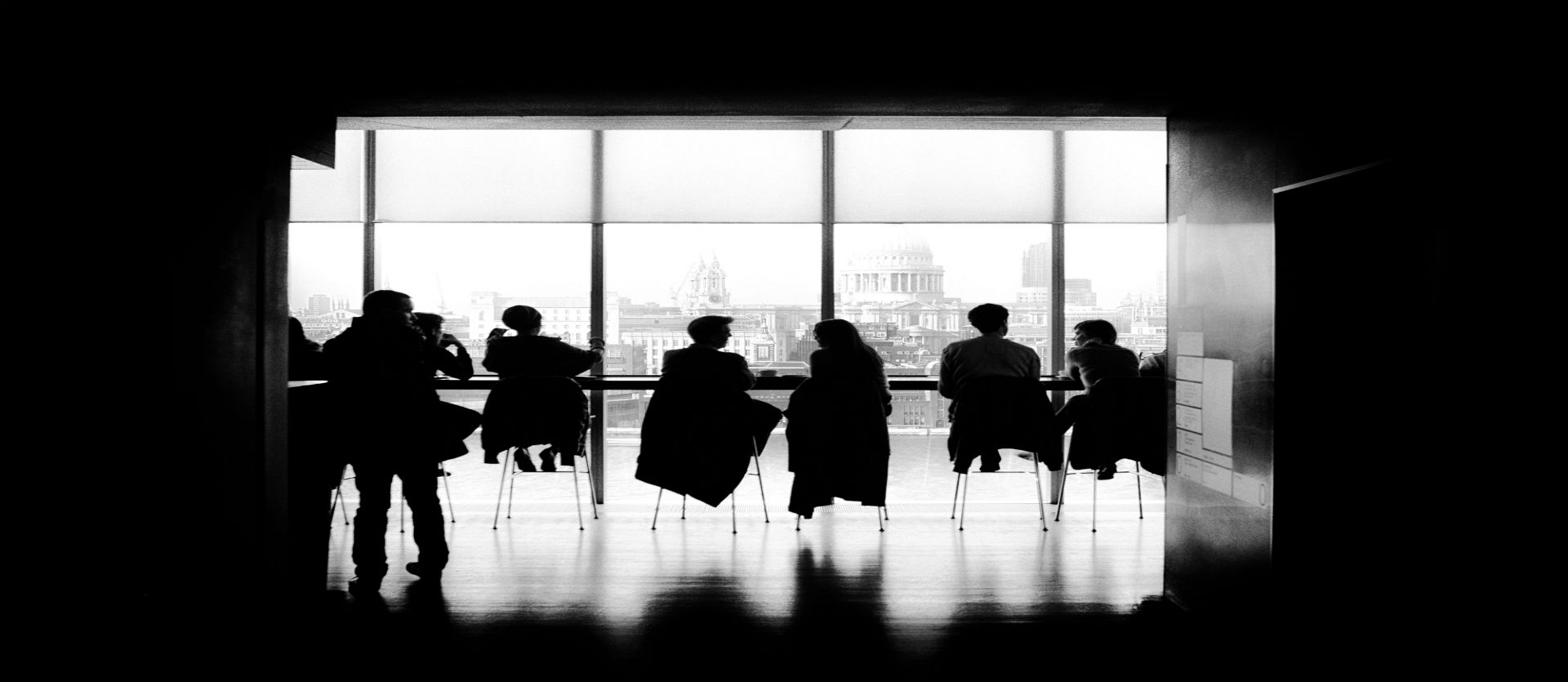 a photo of people sitting around a table in front of the Thames river by Samuel Zeller